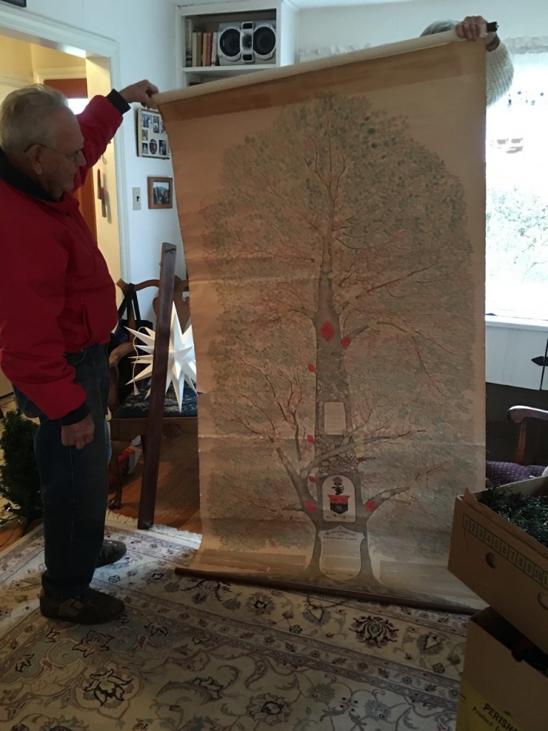 Bill Hall holds up the huge Lippincott Family Tree with help from his wife Nancy, standing on chair.